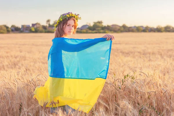 Buğday tarlasında mavi-sarı Ukrayna bayrağı olan bir kız. Ukrayna 'nın bağımsızlık günü, anayasa günü, bayrak günü.