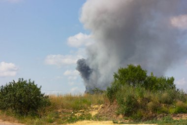 Ufuktaki koyu gri duman sütunu. Açık alanda yangın.