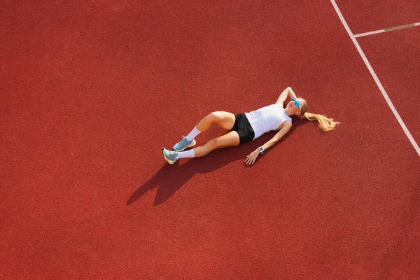 Eğitimden ve spor egzersizlerinden sonra stadyumdaki genç bayan dinleniyor. Spor eğitimi, fitness, sağlıklı yaşam tarzı konsepti.