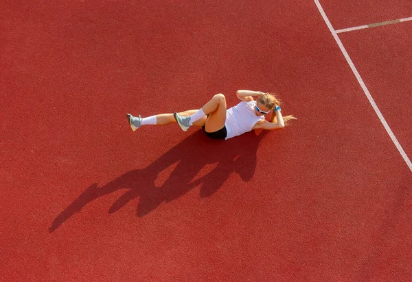 Stadyumda oturan genç kadın spor egzersizleri yapıyor. Spor eğitimi, fitness, sağlıklı yaşam tarzı konsepti.