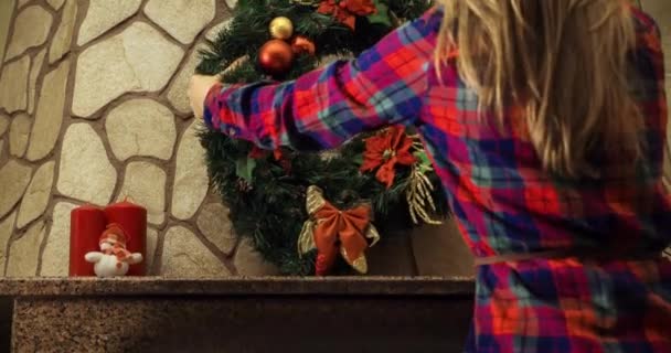 Mujer decorando chimenea para Navidad con corona — Vídeos de Stock