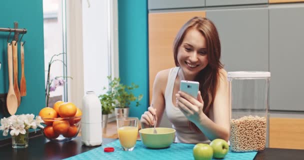Жінка зі смартфоном їсть здоровий сніданок — стокове відео