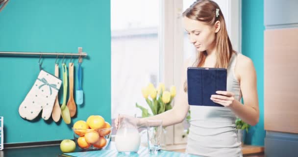 Woman with tablet pc drinking milk — Stock video