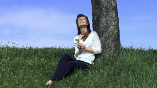 Young woman sitting by tree — ストック動画