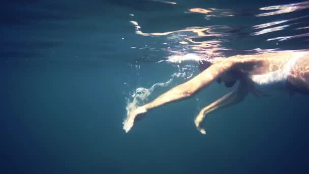 Jeune femme plongée en apnée dans l'eau bleue — Video