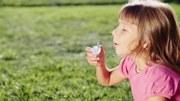 Mała dziewczynka dmuchanie bańki mydlane — Wideo stockowe