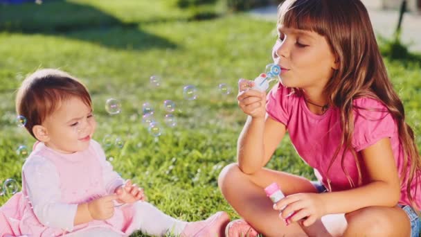 Två små flickor leker på gräsmattan — Stockvideo