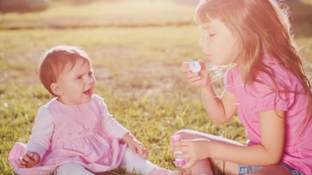 Две маленькие девочки играют на лужайке — стоковое видео