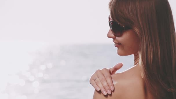 Kvinnan använda solskyddsmedel på hennes axel — Stockvideo