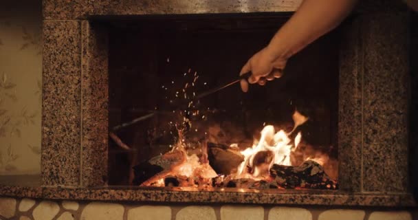 homme déplaçant des grumes dans une cheminée en feu 