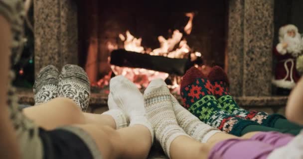 Family with kids warming feet by fire — Stock Video