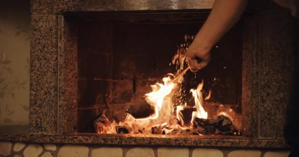 homme déplaçant des grumes dans une cheminée en feu 