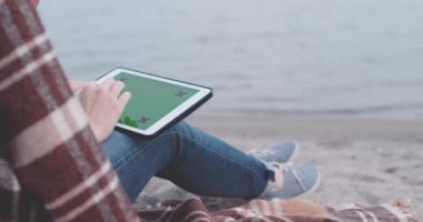 Sahilde dijital tablet kullanan kadın