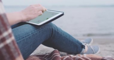 Sahilde dijital tablet kullanan kadın