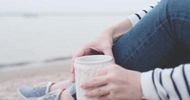 Göl kenarında sıcak kahve içen kadın.