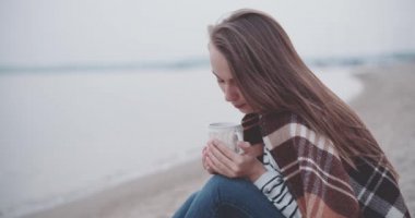 Göl kenarında sıcak kahve içen kadın.