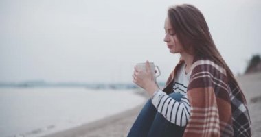 Göl kenarında sıcak kahve içen kadın.