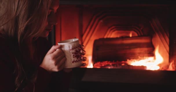 Mujer con taza de té caliente cerca de la chimenea — Vídeos de Stock