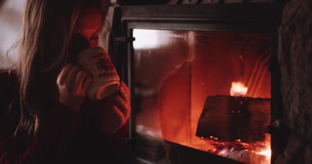 Mujer con taza de té caliente cerca de la chimenea — Vídeos de Stock