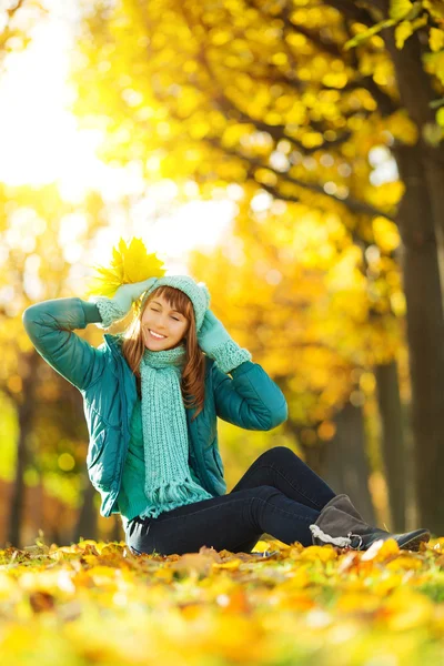 Vrouw zitten op grond in herfst park. — Stockfoto