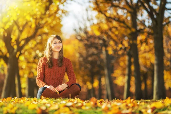 Frau sitzt im Herbstpark auf dem Boden. — Stockfoto