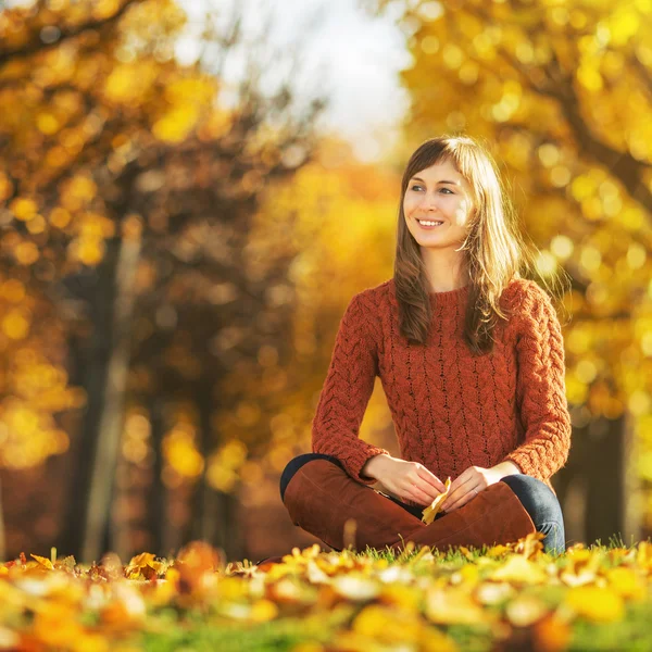 Sonbahar Park zeminde oturan kadın. — Stok fotoğraf