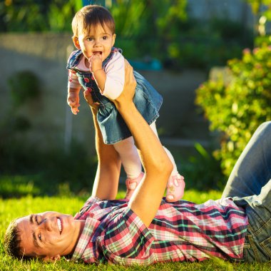 Baba ve bebek kızı güneşli bahçede eğleniyor.