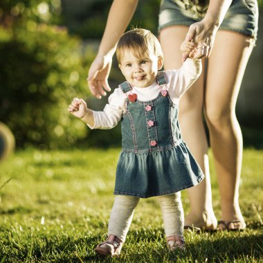 Kız bebek ilk adımlarını anneler yardımıyla yapıyor