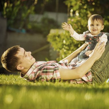 Baba ve bebek kızı güneşli bahçede eğleniyor.