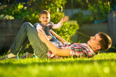 Baba ve bebek kızı güneşli bahçede eğleniyor.