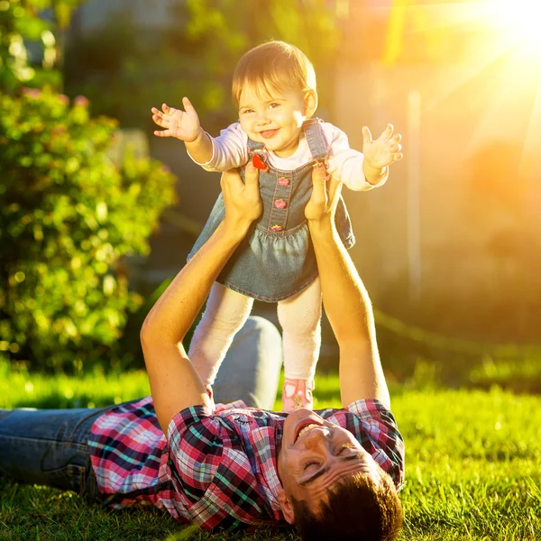 Pappa och baby dotter ha kul i soliga trädgård. — Stockfoto