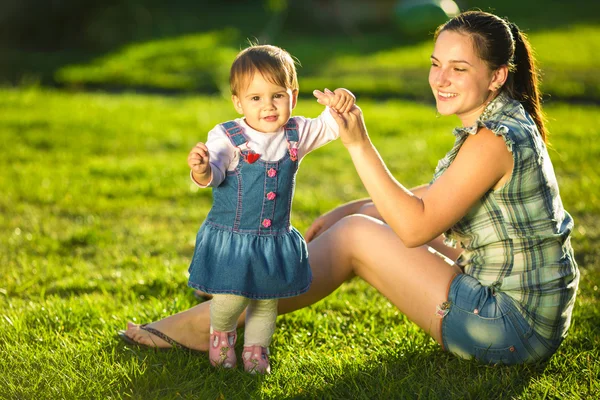 Bebé niña está haciendo sus primeros pasos con las madres ayudan —  Fotos de Stock