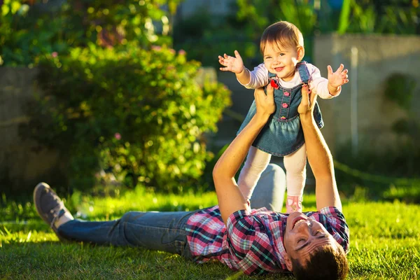 Pappa och baby dotter ha kul i soliga trädgård. — Stockfoto