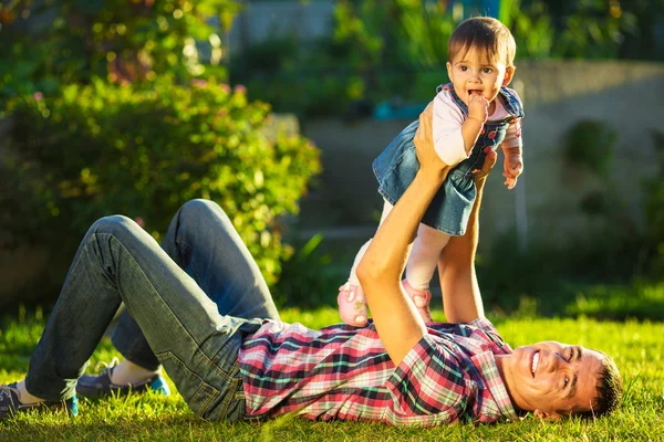 Vater und kleine Tochter amüsieren sich im sonnigen Garten. — Stockfoto