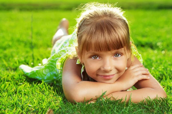 Petite fille allongée sur une herbe verte — Photo