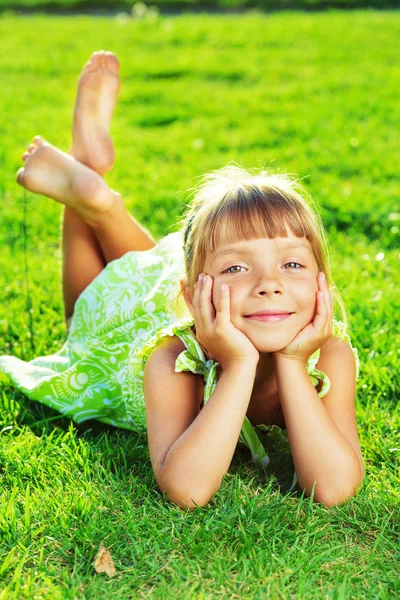 Menina deitada em uma grama verde — Fotografia de Stock