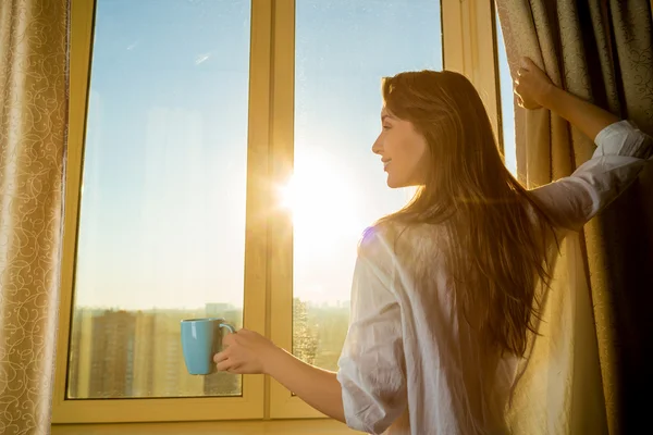 Nő a gazdaság csésze teát, és keresi a sunrise — Stock Fotó