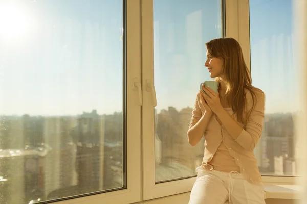 Woman holding cup of tea and looking at  sunrise — Stock Photo, Image