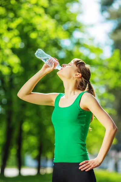 Woman drinking water from bottle in park