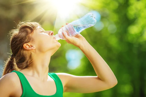 Femme eau potable de la bouteille dans le parc — Photo