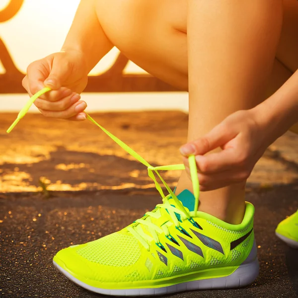 Vrouw koppelverkoop veters op loopschoenen — Stockfoto