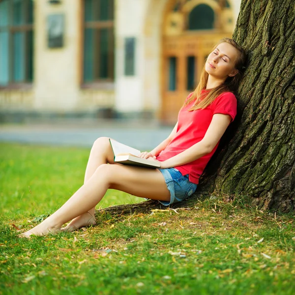 Étudiante rêvant près d'un arbre avec livre — Photo