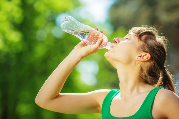 女性が公園でボトルから水を飲む ストックフォト