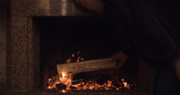 Hombre poniendo troncos en la chimenea — Vídeo de stock