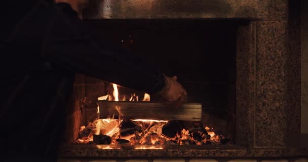 Hombre poniendo troncos en la chimenea — Vídeos de Stock