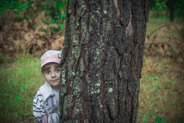 Uma Menina Loira Esconde Atrás Uma Árvore Foto Alta Qualidade — Fotografia de Stock