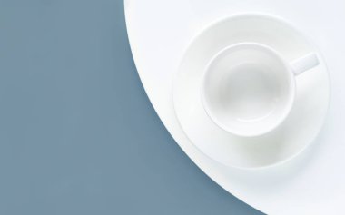 Mavi ve beyaz arka planda boş beyaz bardak. Düz yerde, üst tarafta, tepede. İçki için hazırlan. Minimalizm.