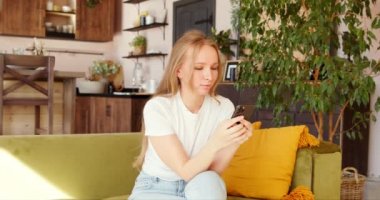 Genç, şaşkın ve şaşırmış bir kadın telefonda iyi haberler okuyor, seviniyor ve evet diye bağırıyor. Mobil uygulama oyununda zaferi kutlayan şanslı kadın..