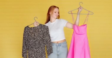 Genç bir kadın toplantıya gidiyor, sarı arka planda kıyafet seçiyor. Ne giyeceğine karar vermek zor.. 