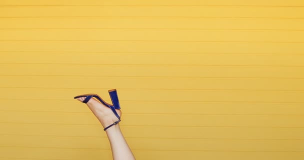 穿着高跟鞋的年轻女子的脚在黄色的背景上倒挂在空中 时尚女鞋的概念 — 图库视频影像